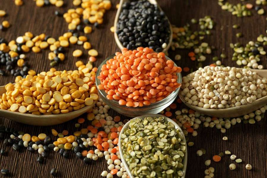 Assorted lentils and legumes in wooden spoons on wooden table. — Lentils Wallpaper