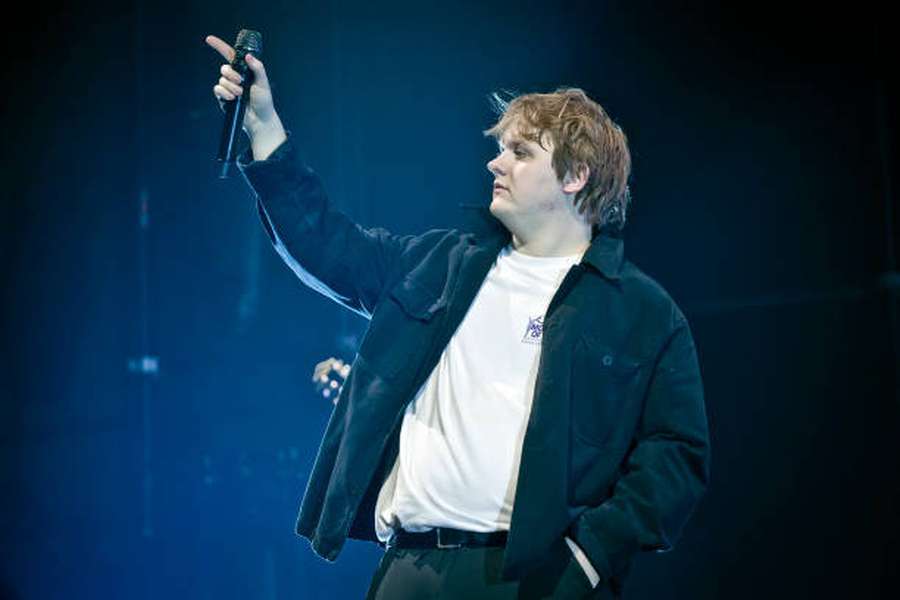 Male musician performing on stage under blue stage lights. — Lewis Capaldi Background