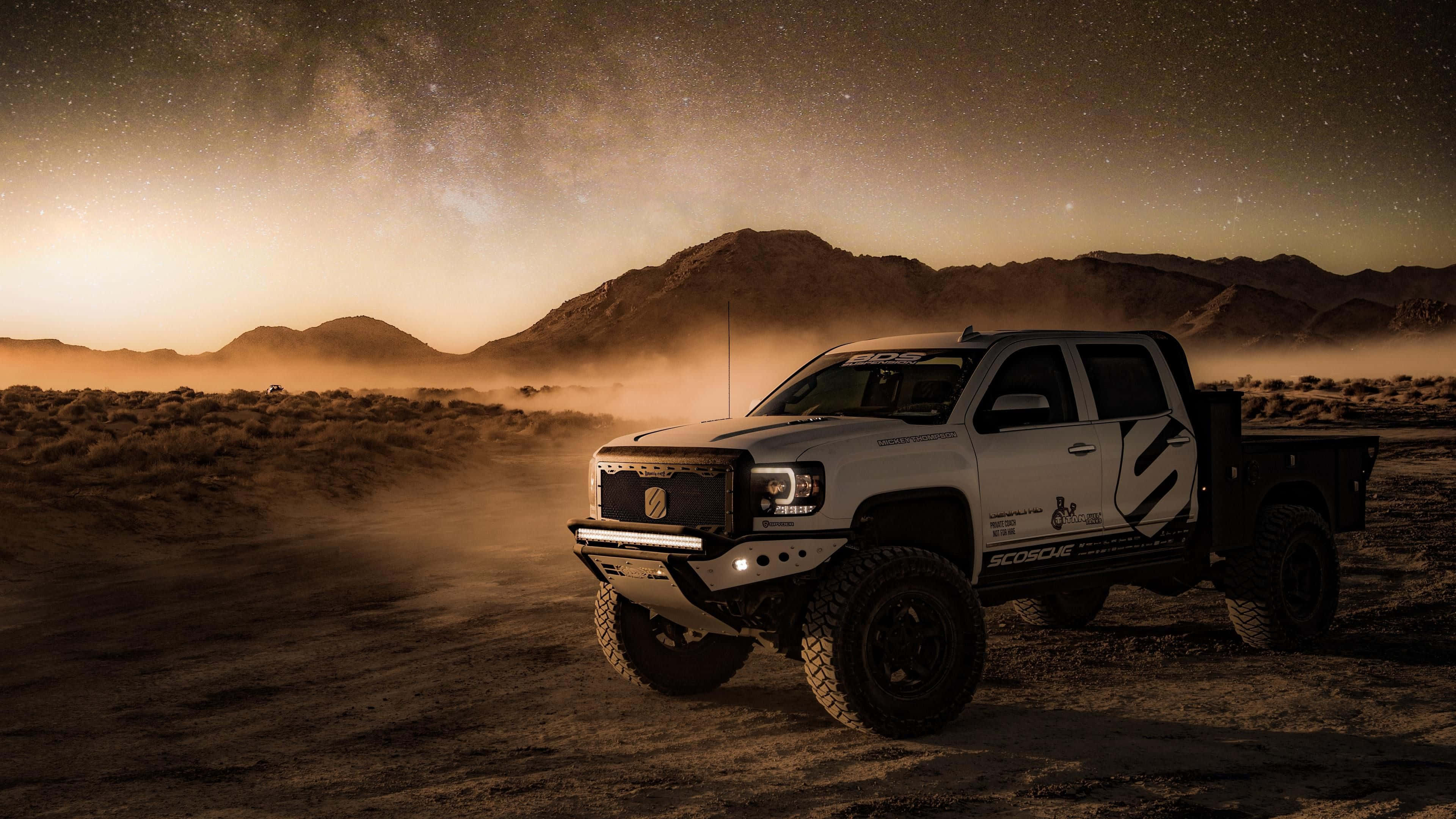 White off-road truck driving through desert at dusk under starry sky — Lifted Truck Wallpaper
