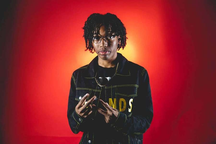 Junge Person mit Dreadlocks und Brille posiert in einem rot beleuchteten Studio. — Lil Tecca Bilder