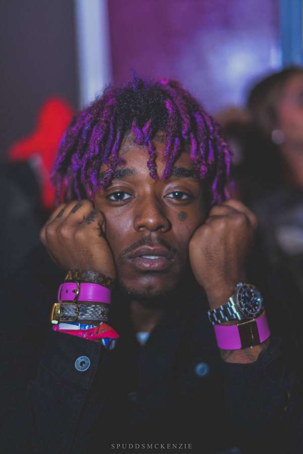 Young man with purple dreadlocks and pink accessories at a nightclub. — Lil Uzi Vert Wallpaper