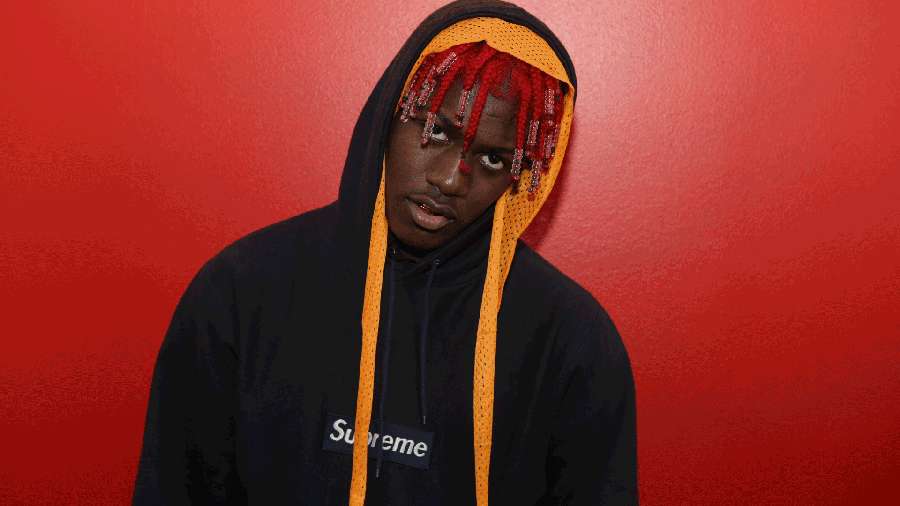 Young man in black Supreme hoodie with red braids against red wall. — Lil Yachty Wallpaper