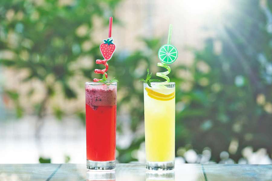 Dos bebidas de frutas coloridas con pajitas decorativas en una mesa al aire libre. — Lima Fondos de pantalla
