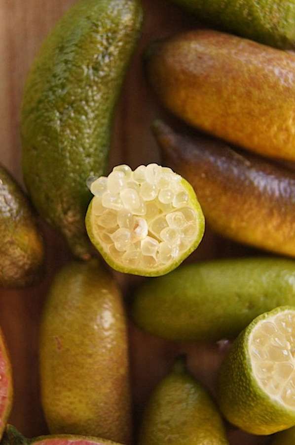 Aufgeschnittene Kumquats mit saftigen Segmenten auf einem Holzbrett. — Limette Wallpaper