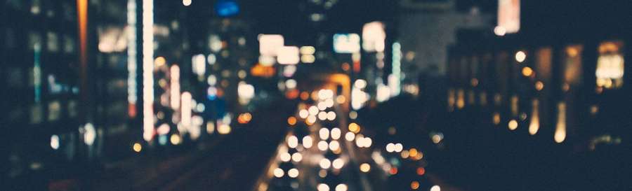 Nighttime city street with blurred lights from buildings and cars. — Linkedin Cover Wallpaper