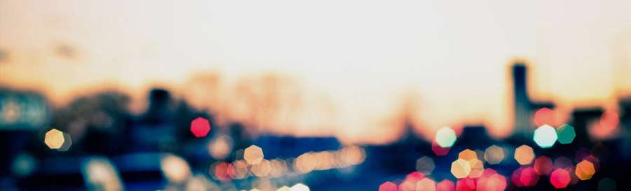 Stadtlichter verschwimmen zu farbenfrohem Bokeh vor einem Sonnenuntergangshimmel. — Linkedin Titelseite Wallpaper
