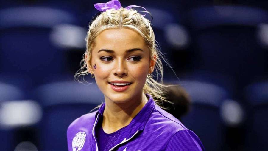 Blonde female tennis player smiling in purple uniform at indoor stadium. — Livvy Dunne Wallpaper