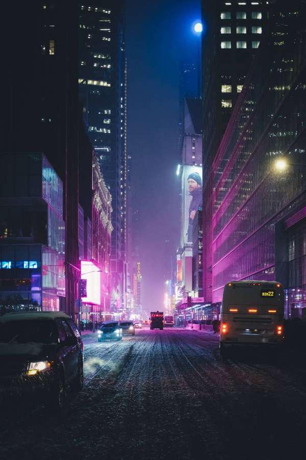 Strada urbana innevata di notte illuminata da insegne al neon e luci dei veicoli. — Lofi Sfondi