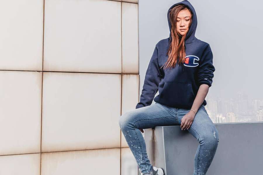 Joven en sudadera y jeans sentada en el borde del techo con vista a la ciudad — Logo de Campeón Fondos de pantalla