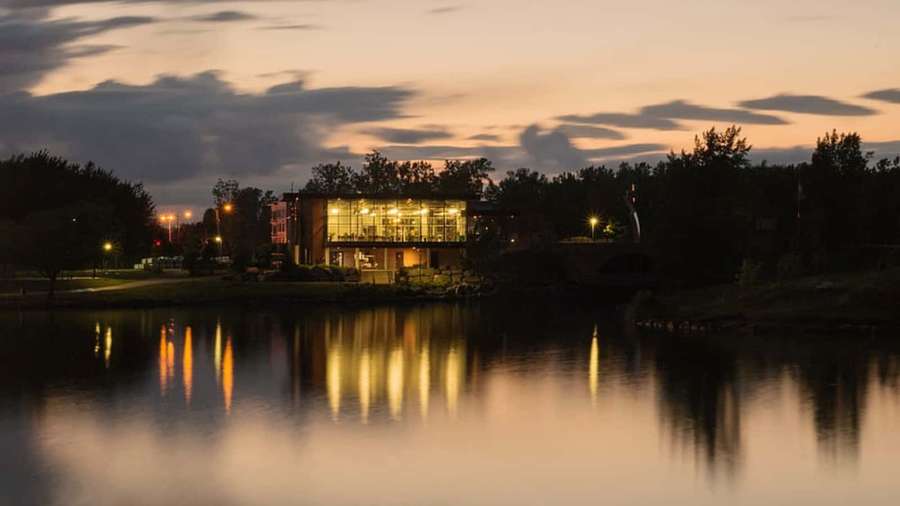 Modern glass building lit at dusk with reflections on calm water — Longueuil Wallpaper