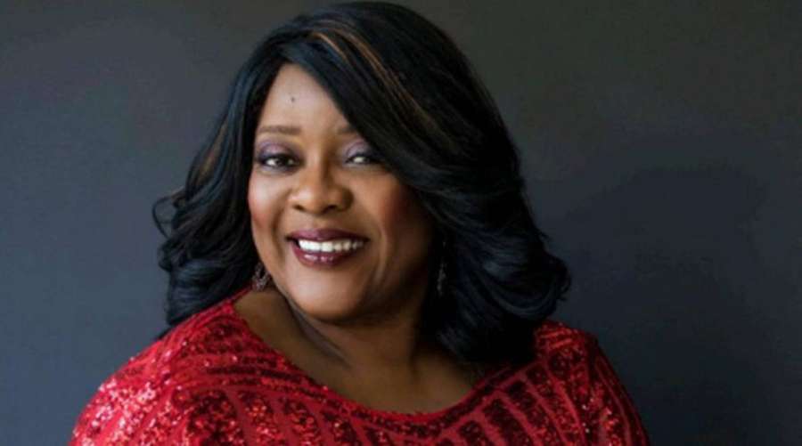 A smiling woman in a red sequined top against a dark gray background. — Loretta Devine Wallpaper