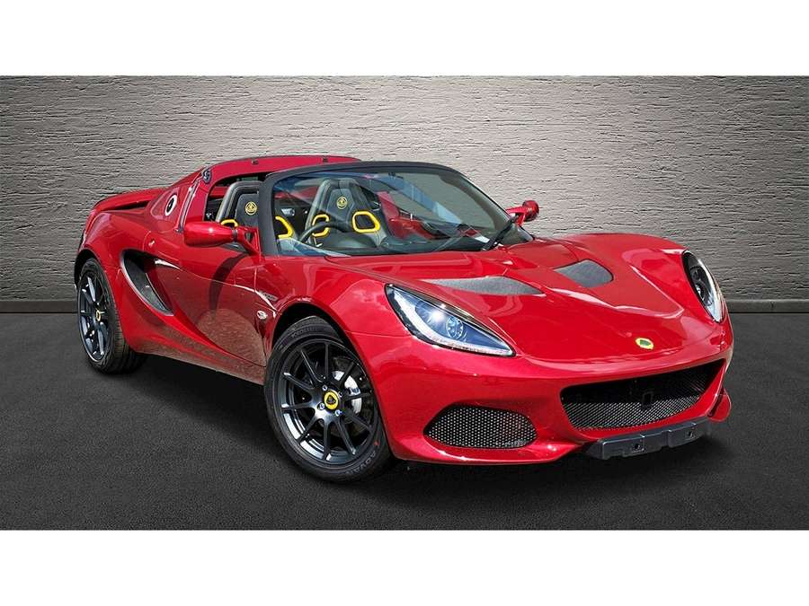 Red Lotus sports car with black wheels and yellow seats against gray wall. — Lotus Car Wallpaper