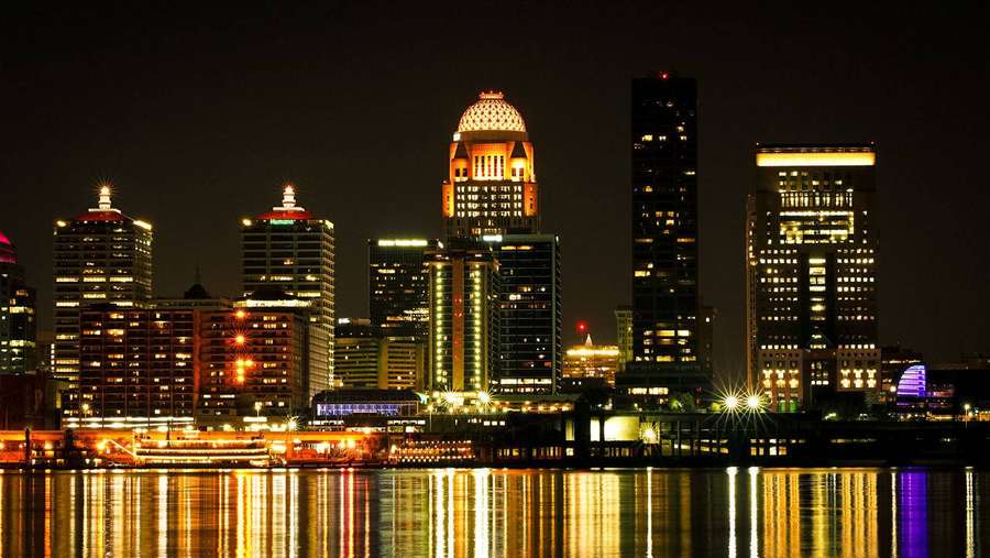 City skyline at night with lights reflecting on water — Louisville Wallpaper