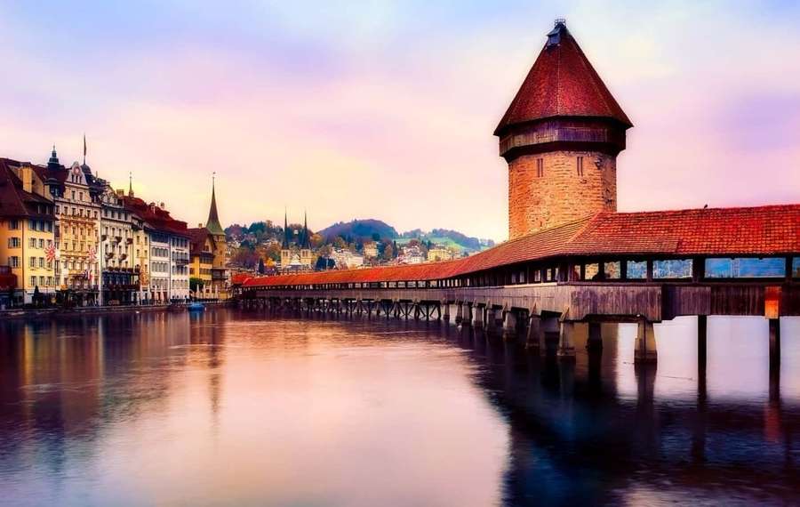 Covered bridge with tower over river at sunset reflecting in calm water. — Lucerne Wallpaper