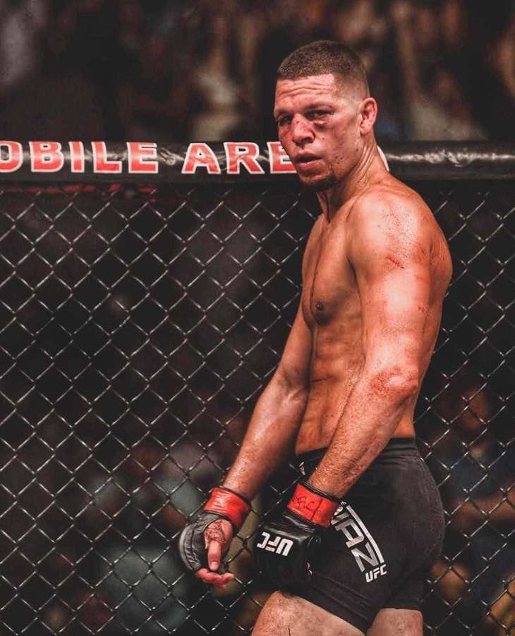 Un luchador de MMA magullado con equipo de la UFC se apoya en la jaula octagonal después de una pelea. — Luchando Fondos de pantalla