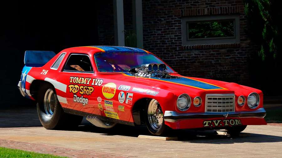 Roter und blauer Vintage-Dragster geparkt auf Ziegelterrasse vor Backsteingebäude. — Lustige Autos Bilder