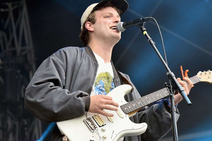 Musiker spielt Gitarre und singt bei einem Live-Konzert unter blauen Bühnenlichtern. — Mac demarco Wallpaper
