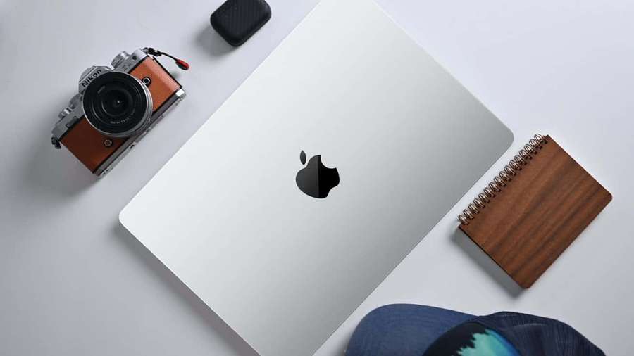 Silver laptop with camera notebook and cap on a clean white desk. — Mac Picture