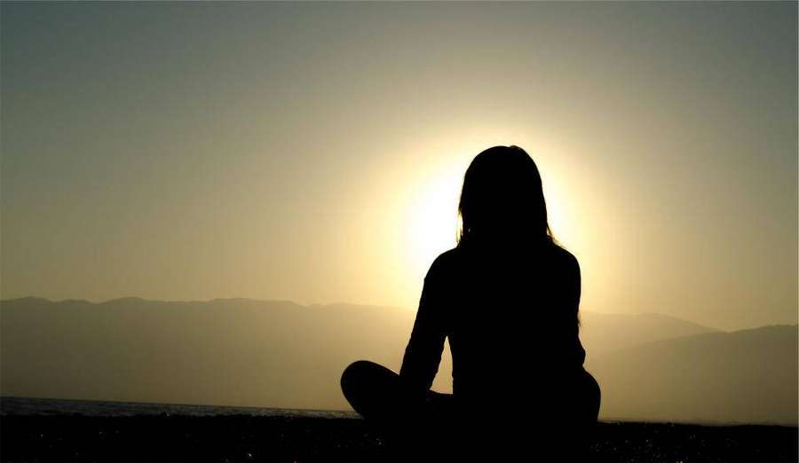 Person meditiert als Silhouette vor einem goldenen Sonnenuntergang über fernen Bergen. — Mädchen Shadow Wallpaper