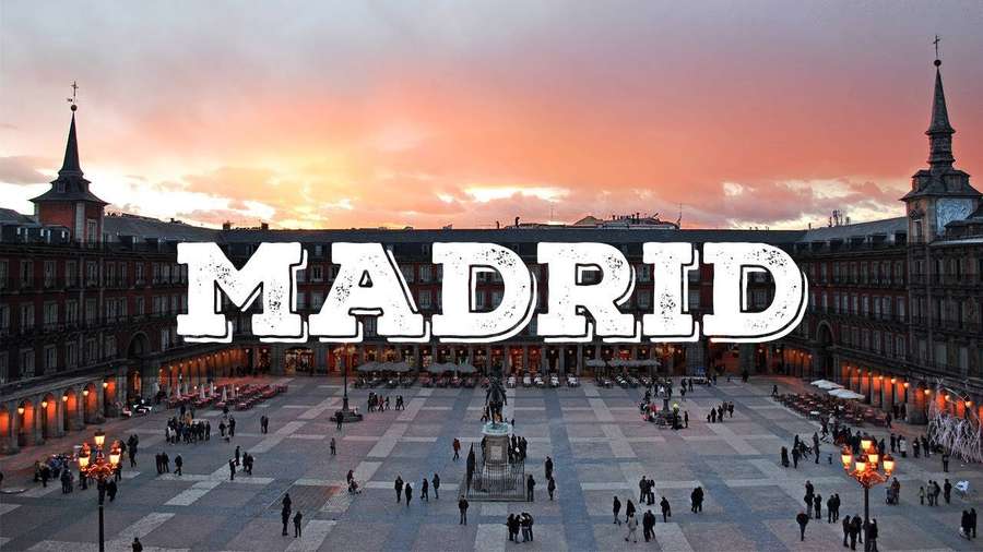 Plaza Mayor de Madrid ao pôr do sol com pessoas caminhando e edifícios históricos iluminados. — Madrid Papéis de Parede