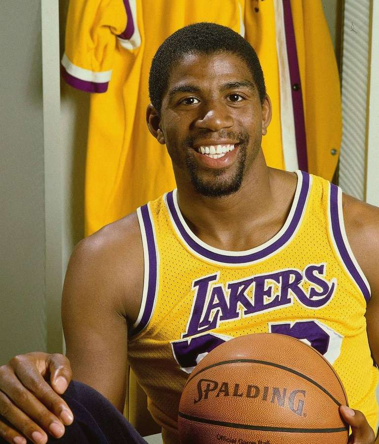 Basketball player in Lakers jersey holding a Spalding ball in locker room. — Magic Johnson Wallpaper
