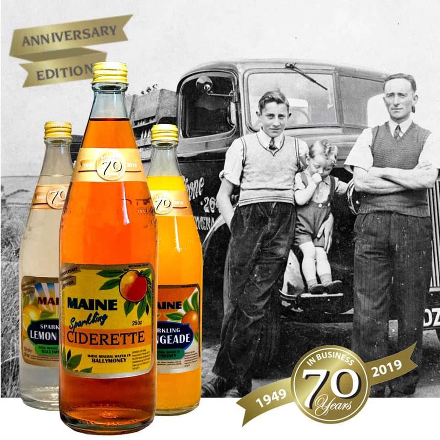 Vintage cider bottles with 70th anniversary logo over a black and white family photo with truck. — Maine Wallpaper
