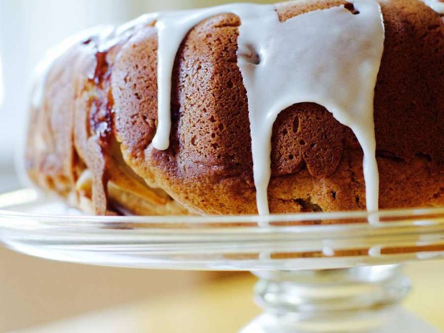 Bolo bundt dourado com glacê branco em suporte de vidro — Manteiga Papéis de Parede