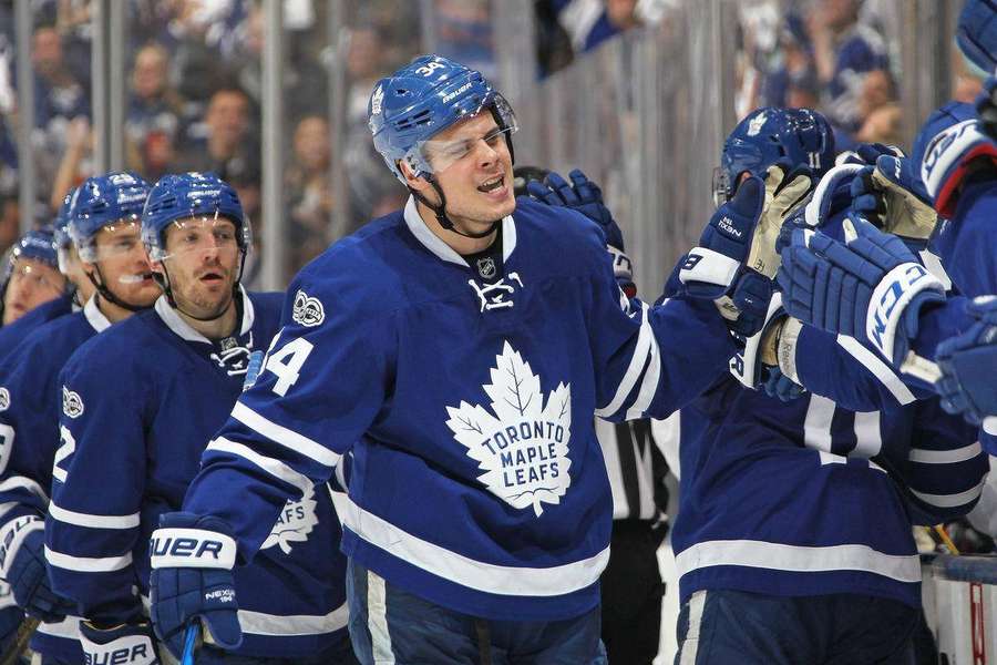 Toronto Maple Leafs hockey players celebrating on the ice. — Maple Background