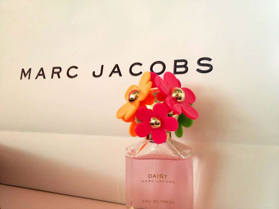 Marc Jacobs Daisy perfume bottle with colorful plastic flower cap on branded packaging. — Marc Jacobs Background