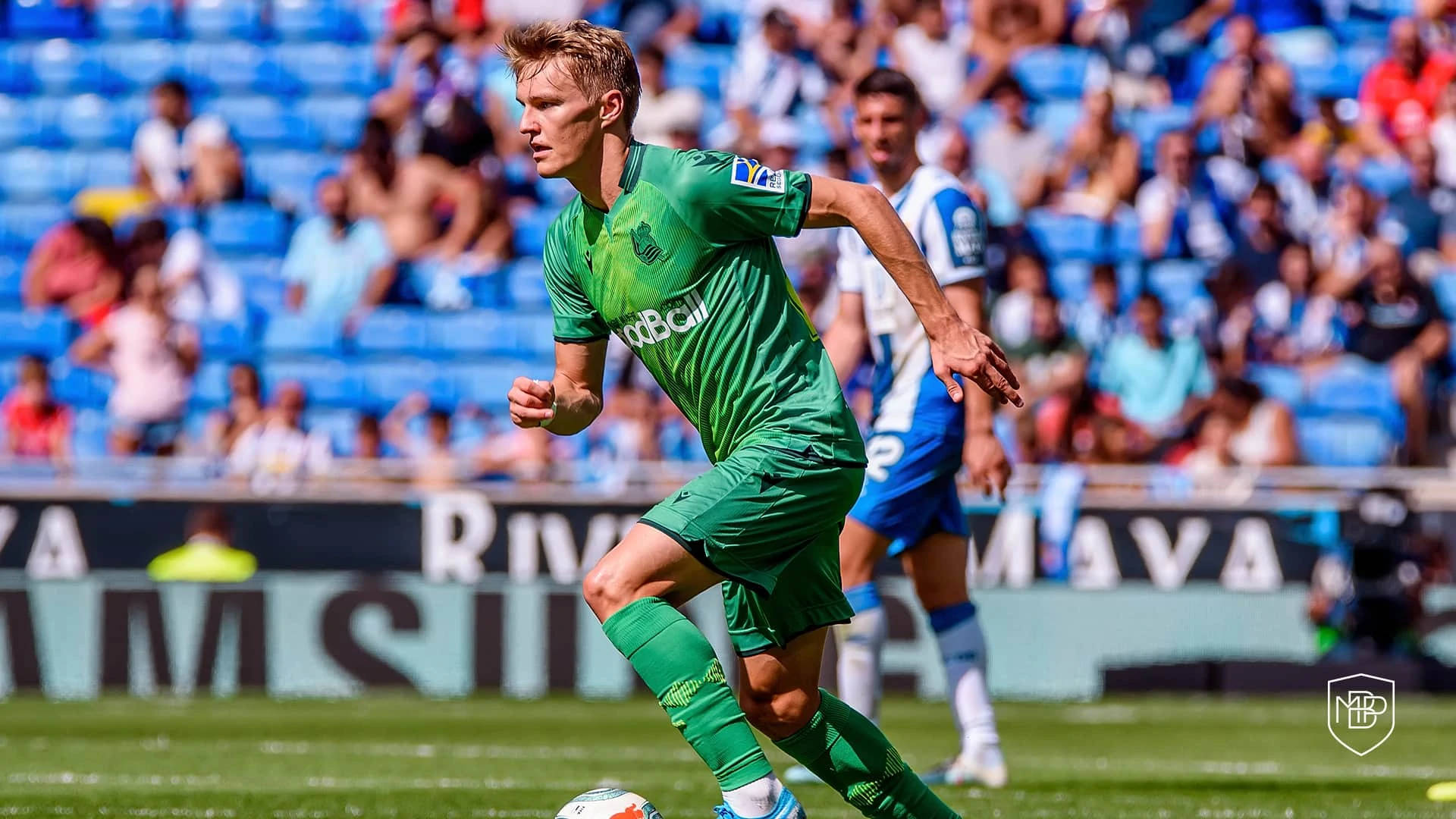 Jalkapalloilija vihreässä paidassa kuljettaa palloa päiväottelussa. — Martin ødegaard Taustakuvat