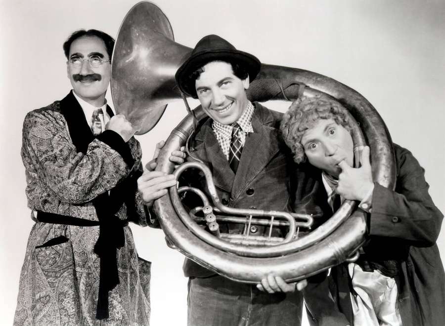 Three men in vintage suits posing with a giant tuba in a studio. — Marx Wallpaper