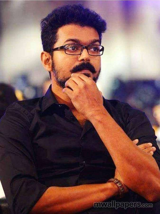A man with glasses and a mustache thinking with his hand on his chin. — Master Vijay Wallpaper
