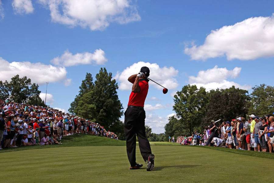 Professional golfer swinging club on sunny course with spectators watching — Masters Background