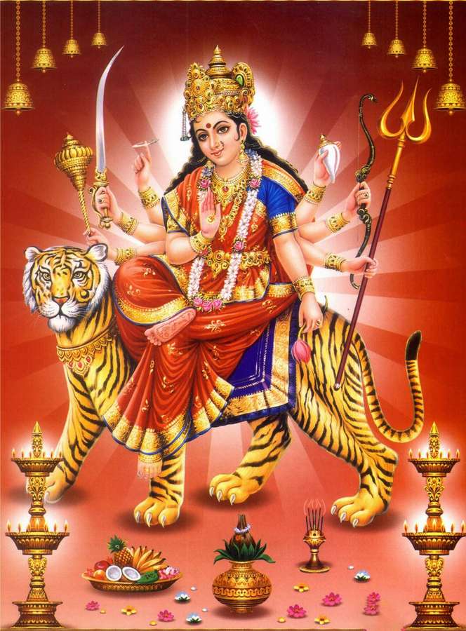 A divine Hindu goddess with multiple arms rides a tiger surrounded by ceremonial items and glowing lights. — Mata Rani Background