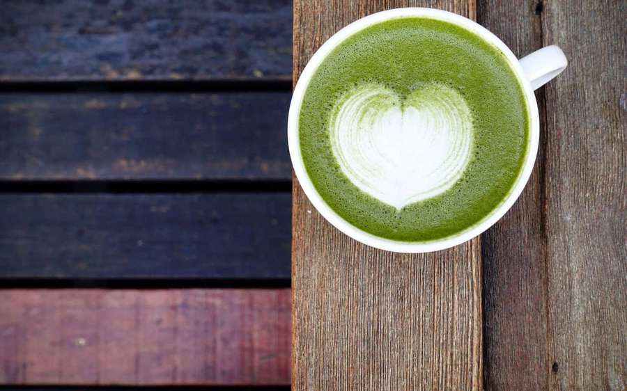 A cup of matcha latte with heart foam on wooden table — Matcha Wallpaper