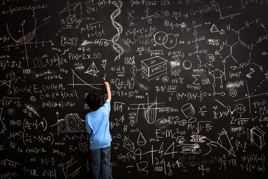 Child solving math problems on a chalkboard covered in equations. — Mathematics Picture