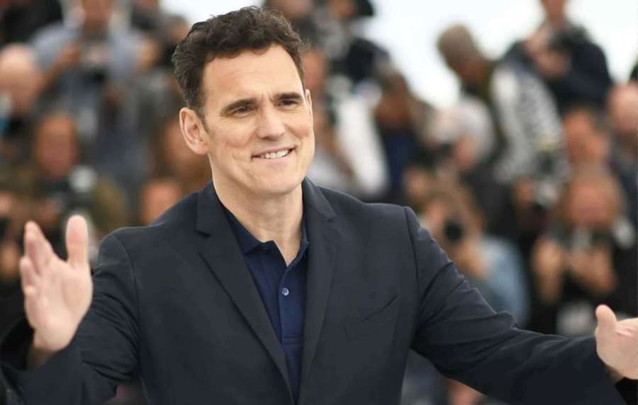 Man in suit smiling and waving to crowd at outdoor event. — Matt dillon Wallpaper
