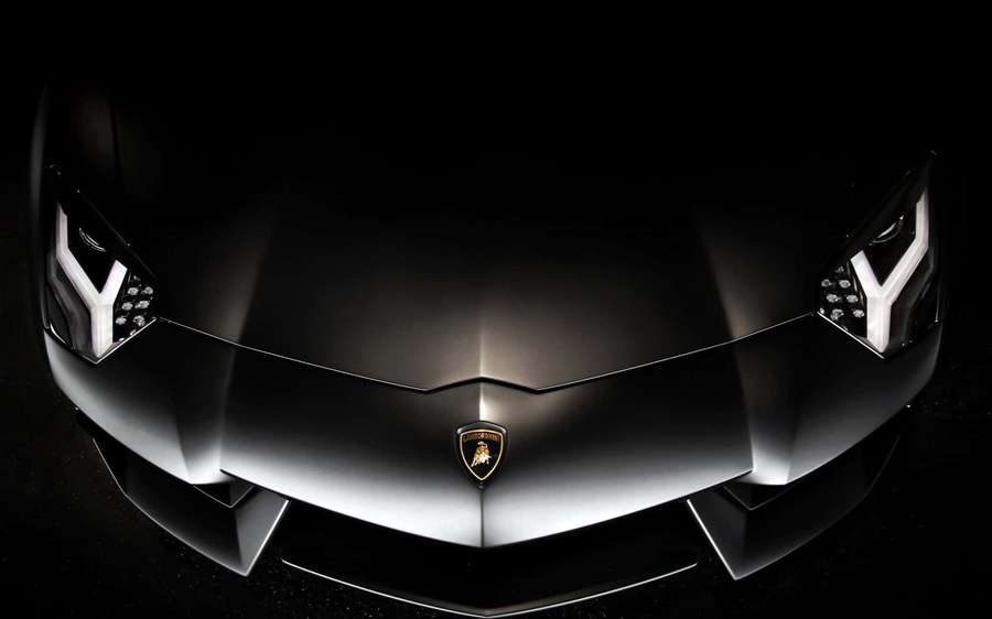 Close-up of a black Lamborghini front with glowing headlights. — Matte Black Background