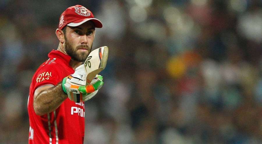 Cricket player in red uniform holding bat during night game. — Maxwell Background