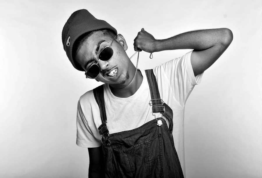 Young man in overalls and sunglasses pulling a chain necklace in a studio shot. — Mc Stan Wallpaper