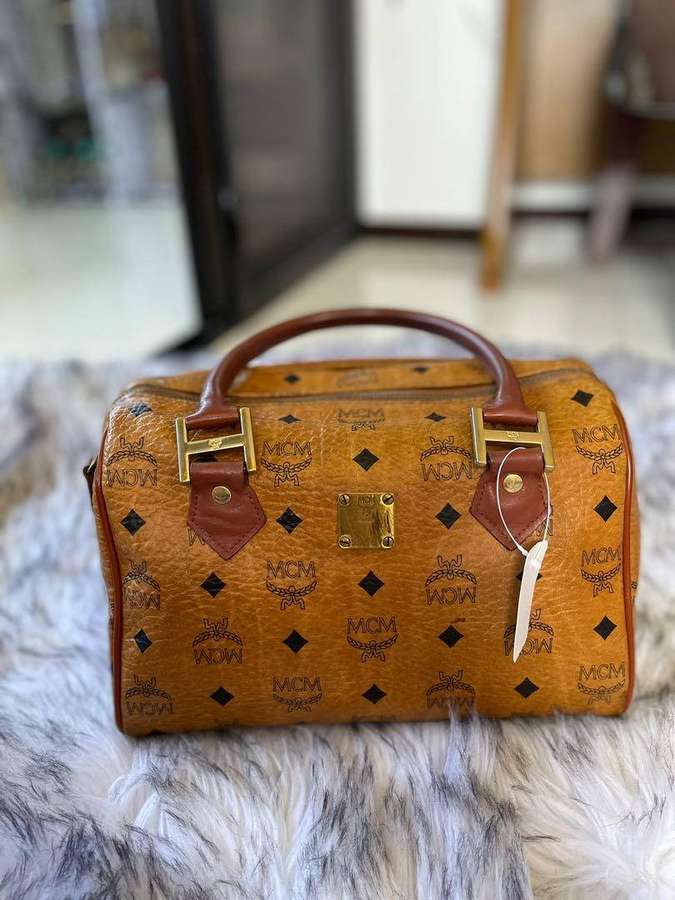 Braune MCM-Handtasche mit Goldbeschlägen auf einem flauschigen Teppich. — Mcm Bilder