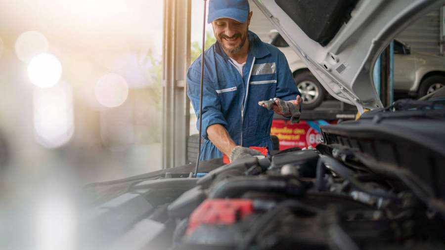 Mechanic checking car engine oil in bright sunlight — Mechanic Wallpaper