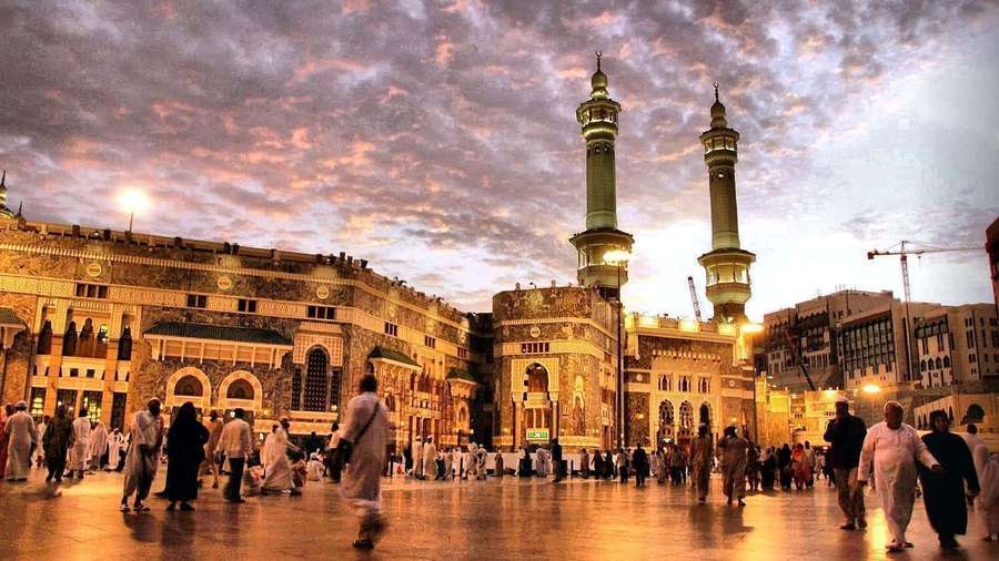 Pilgrims walk across a reflective courtyard before a grand mosque at twilight. — Medina Picture