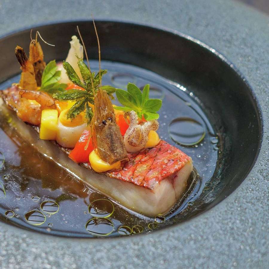 Angebratener Fisch mit Garnelen und Gemüse in dunkler Schale mit Öltropfen — Meerbarbe Wallpaper