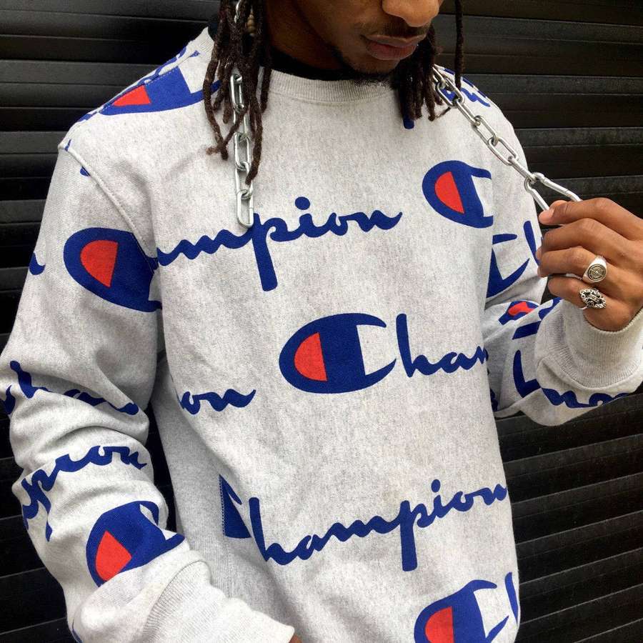 Person in Champion-Sweatshirt hält Kette vor schwarzem Rollladenhintergrund — Meister logo Wallpaper