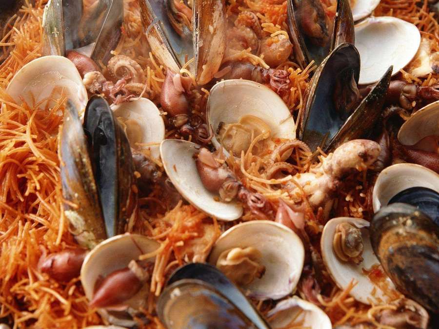 Una colorida paella de mariscos con mejillones, almejas y calamares sobre arroz con azafrán. — Mejillón Fondos de pantalla