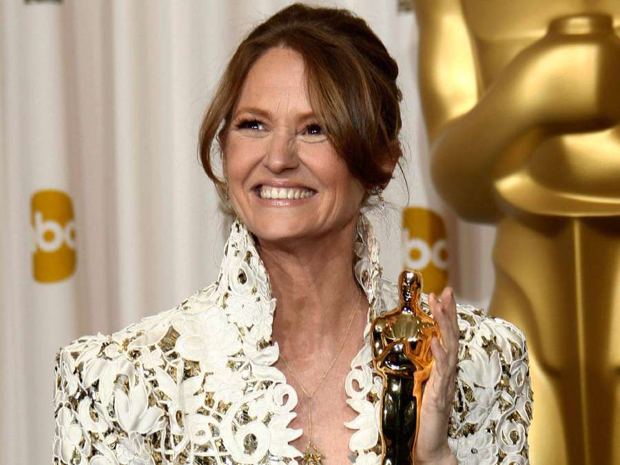 Donna in abito bianco che tiene una statuetta dell'Oscar alla cerimonia di premiazione. — Melissa Leo Sfondi