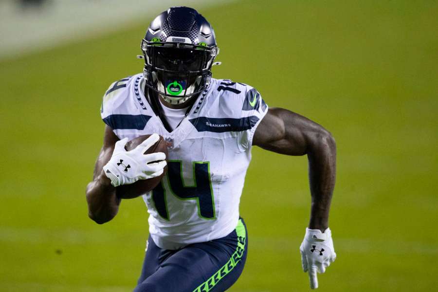 Seattle Seahawks Footballspieler läuft nachts mit dem Ball. — Metcalf Wallpaper