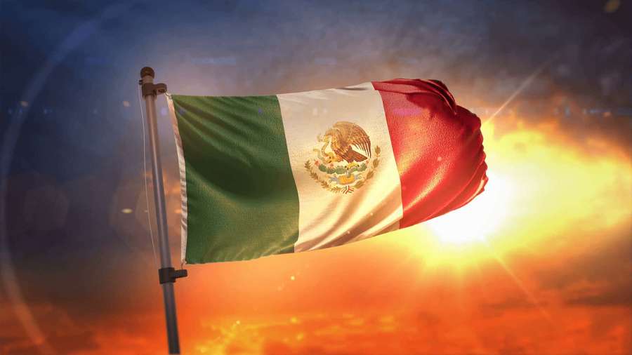 Mexican flag waving in sunset light with glowing sun and fiery sky. — Mexican Background