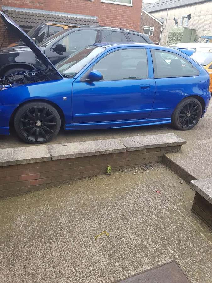 Sininen viistoperäauto avoimella konepellillä pysäköitynä märälle betonipihalle. — Mg Zr Taustakuvat